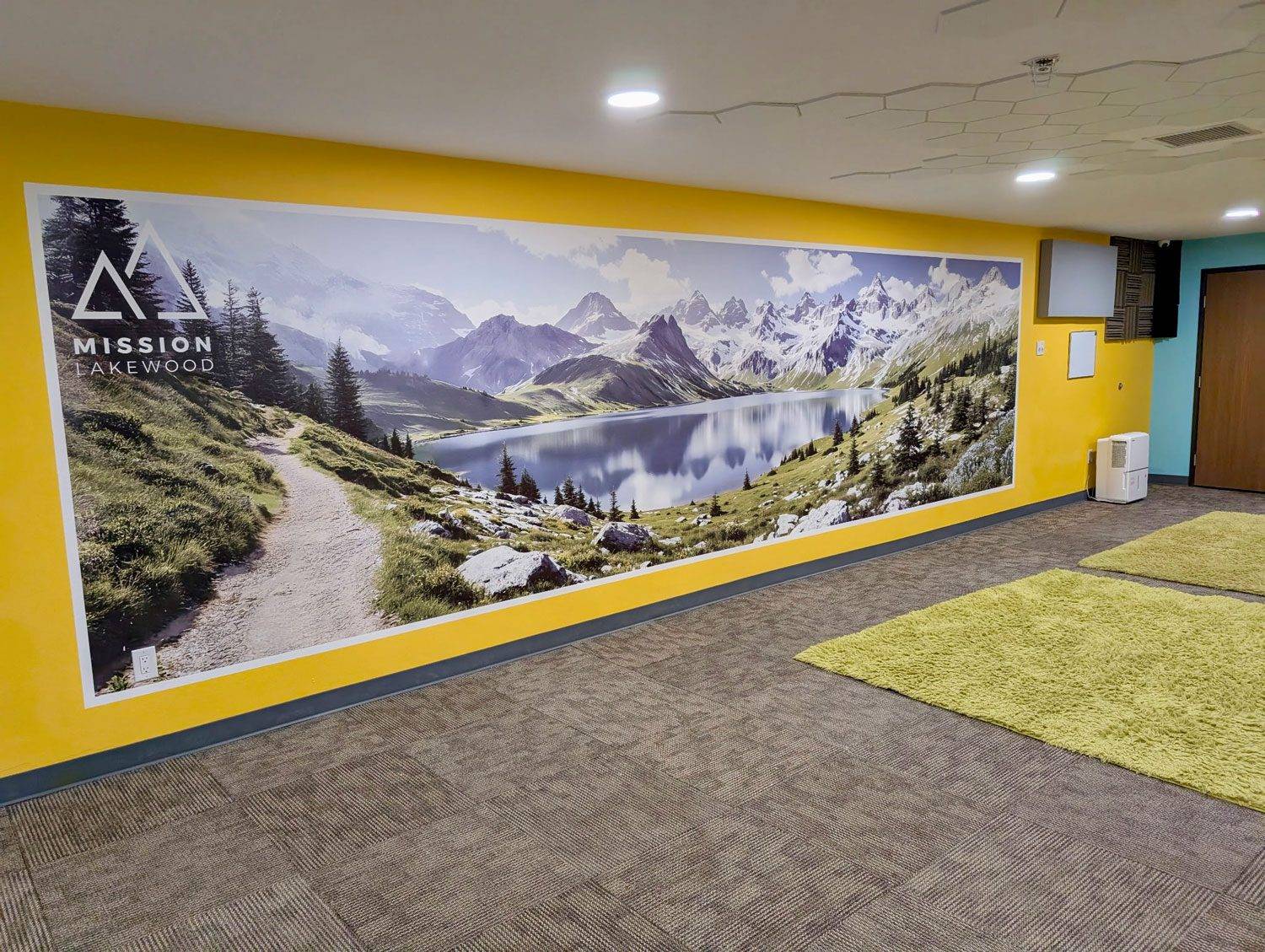 Scenic mountain lake mural printed on a church interior wall with logo branding for Mission Lakewood — professional vertical wall printing by ArtWall Pro.